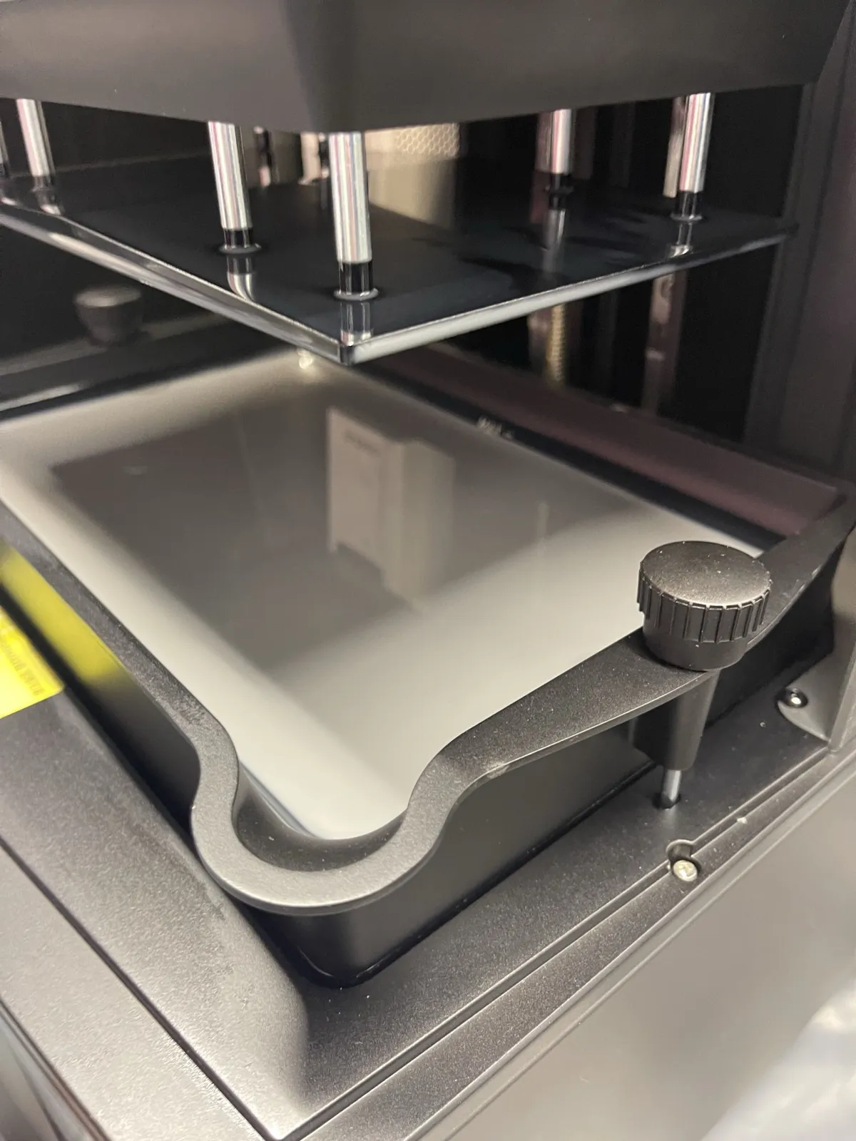 The Saturn's vat seated under the raised build plate, held by its black clamp knob.