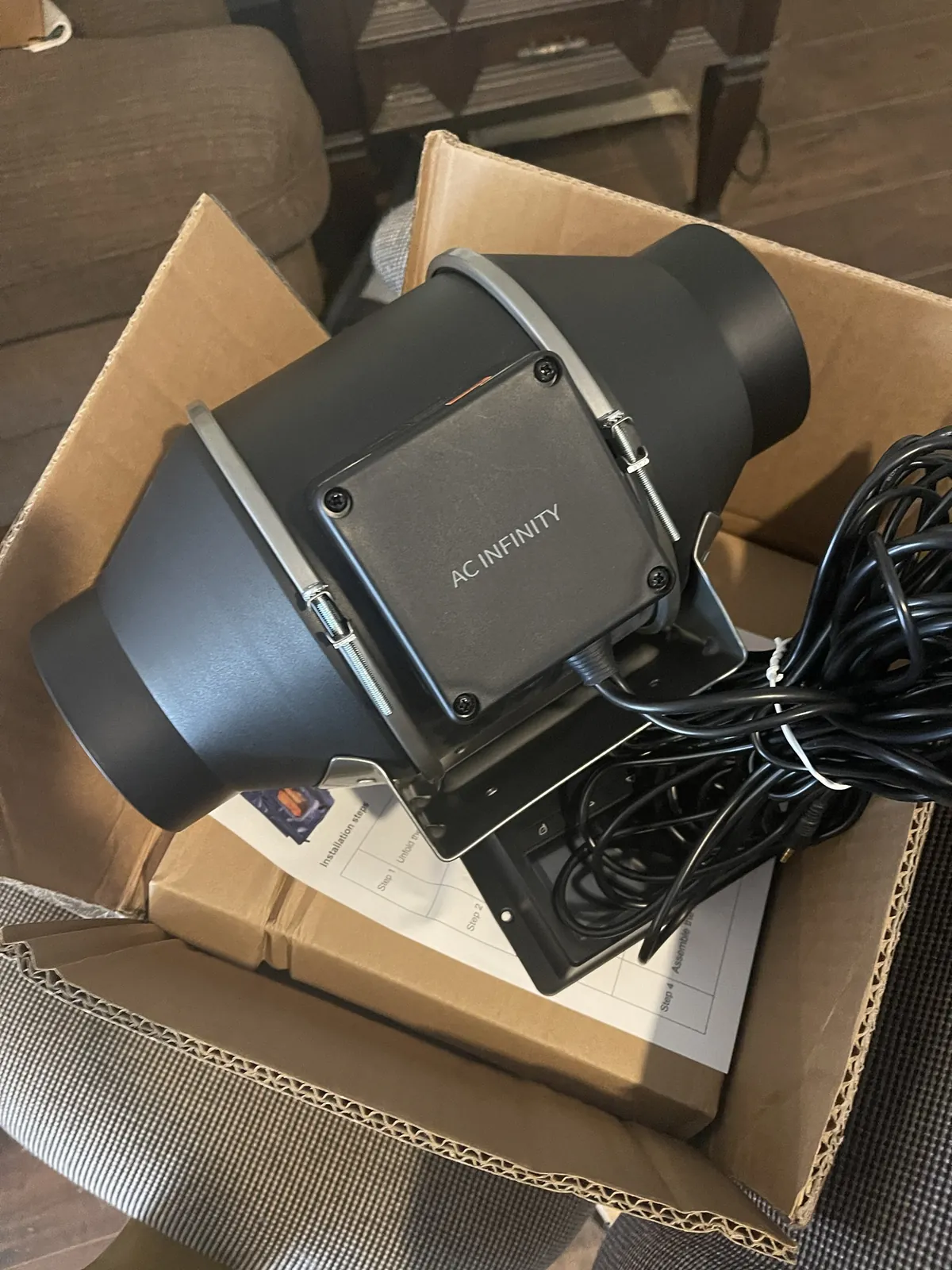 The AC Infinity CLOUDLINE T4 inline fan in its box, with its mounting bracket, coiled cord, and installation sheet.