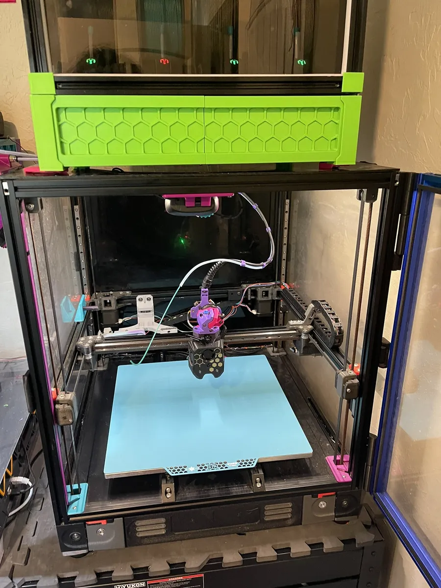 Teresa, an enclosed Voron 2.4 350 with a cyan build plate and multicolor toolhead, with the bright green Box Turtle mounted above.